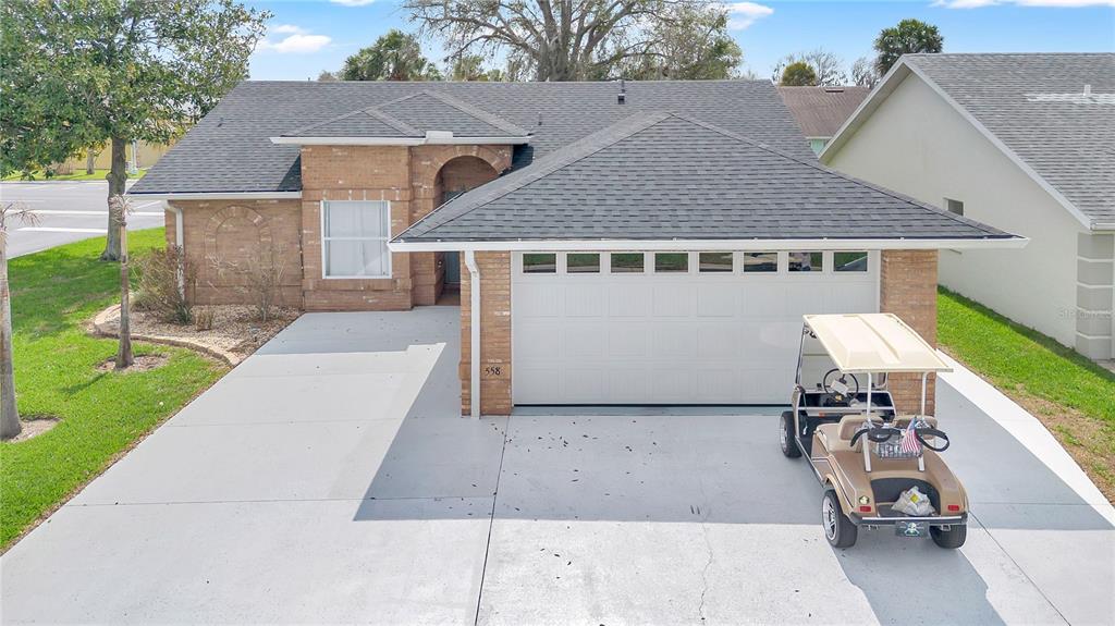 A single-story brick house with a two-car garage and a golf cart in the driveway — 558 PINNACLE DRIVE, HAINES CITY, FL