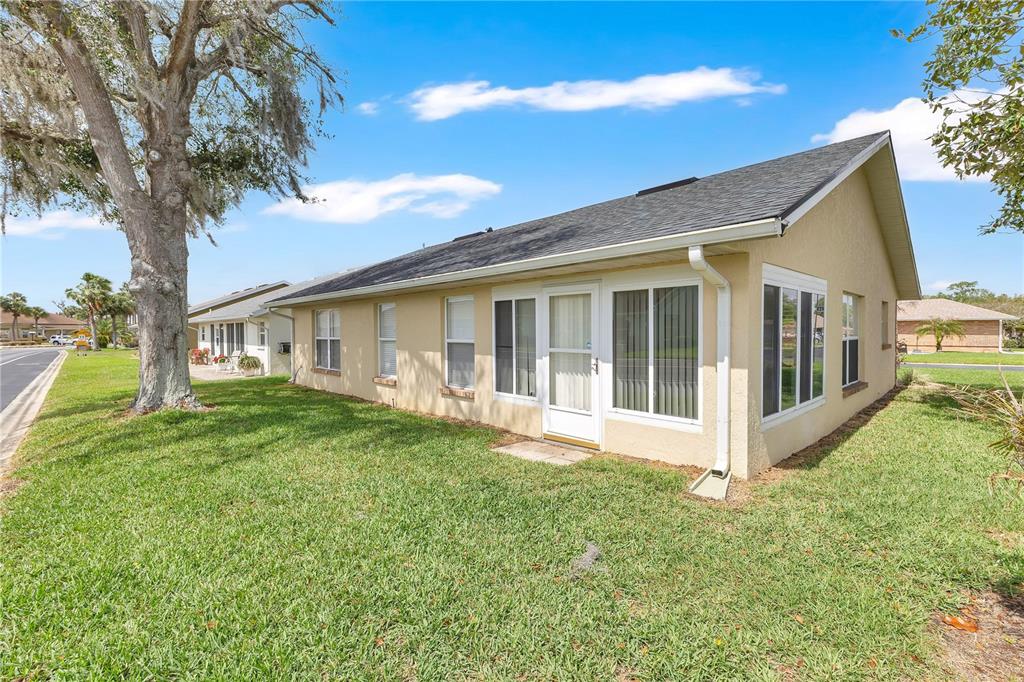 A side view of a single-story tan house with a shingled roof and lawn — 558 PINNACLE DRIVE, HAINES CITY, FL
