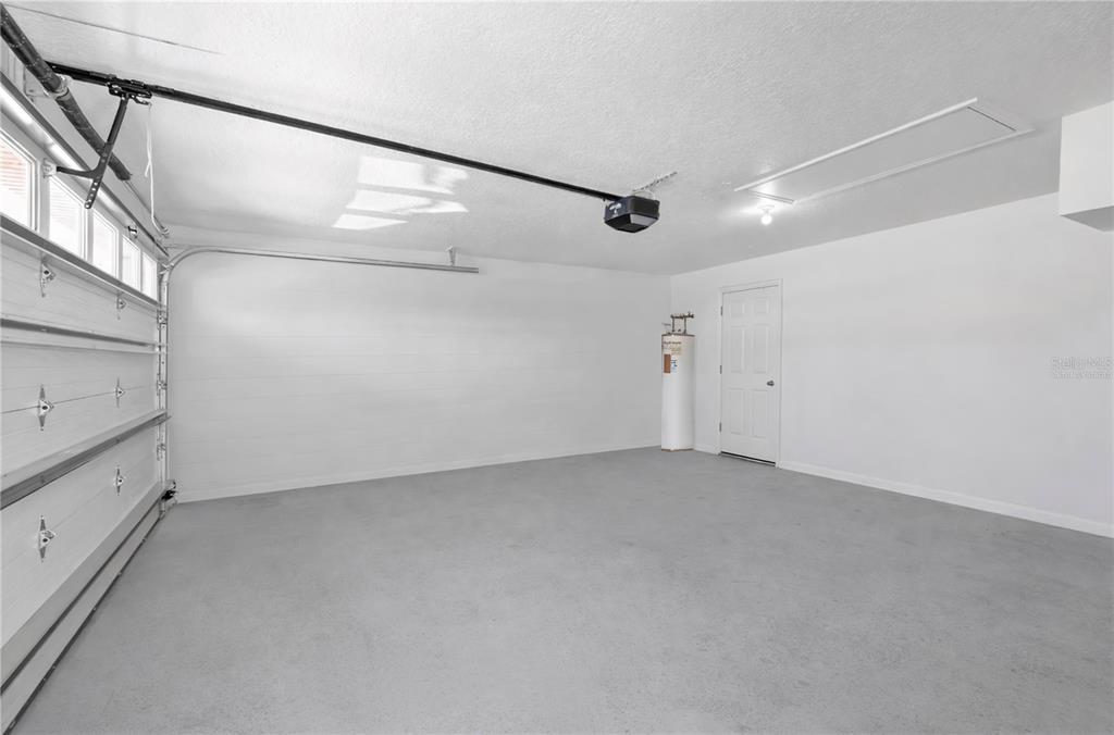 An empty garage with a white door, a water heater, and a concrete floor — 558 PINNACLE DRIVE, HAINES CITY, FL