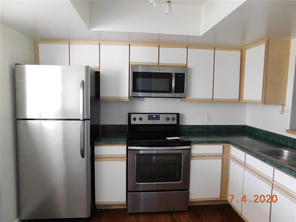 A kitchen features stainless steel appliances, white cabinets with wood trim, and green laminate countertops — 6314 NEWTOWN CIRCLE UNIT 14B3, TAMPA, FL