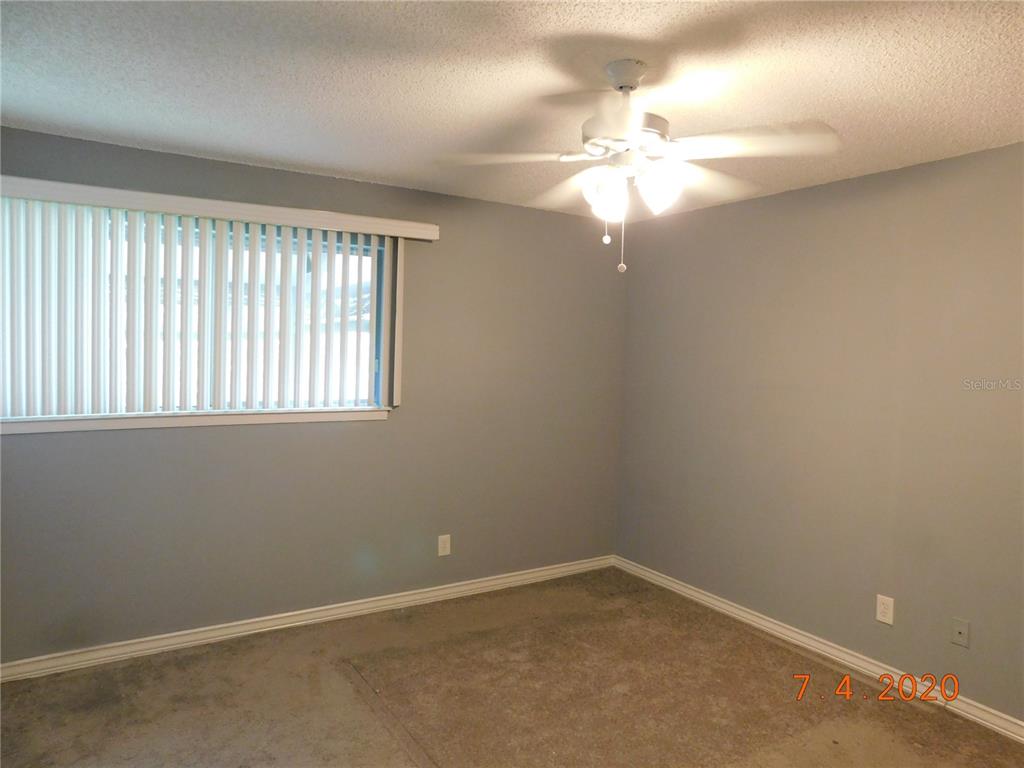 An empty bedroom features gray walls, beige carpeting, a ceiling fan, and vertical window blinds — 6314 NEWTOWN CIRCLE UNIT 14B3, TAMPA, FL