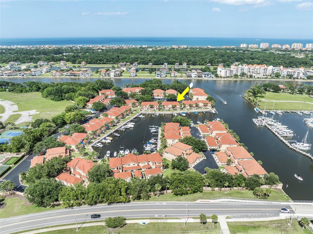 An aerial view shows a waterfront residential complex with boat slips and a nearby road — 50 RIVERS EDGE LANE, PALM COAST, FL