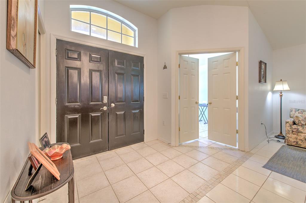 A tiled entryway features a dark double front door and an open doorway to a patio — 30914 BURLEIGH DRIVE, WESLEY CHAPEL, FL