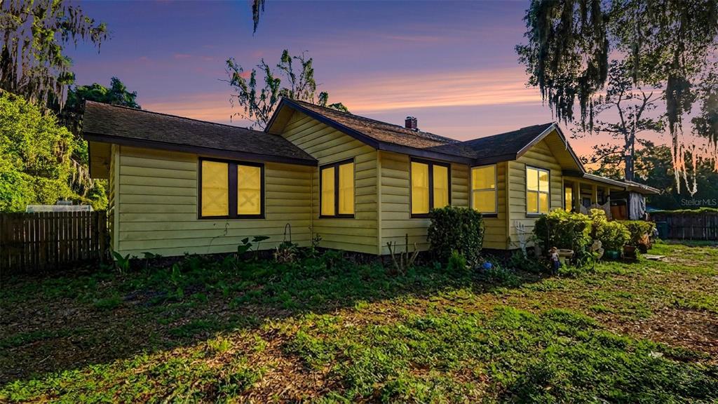 A yellow, single-story house with a dark shingled roof sits on a grassy lot — 833 NE 28TH STREET, OCALA, FL