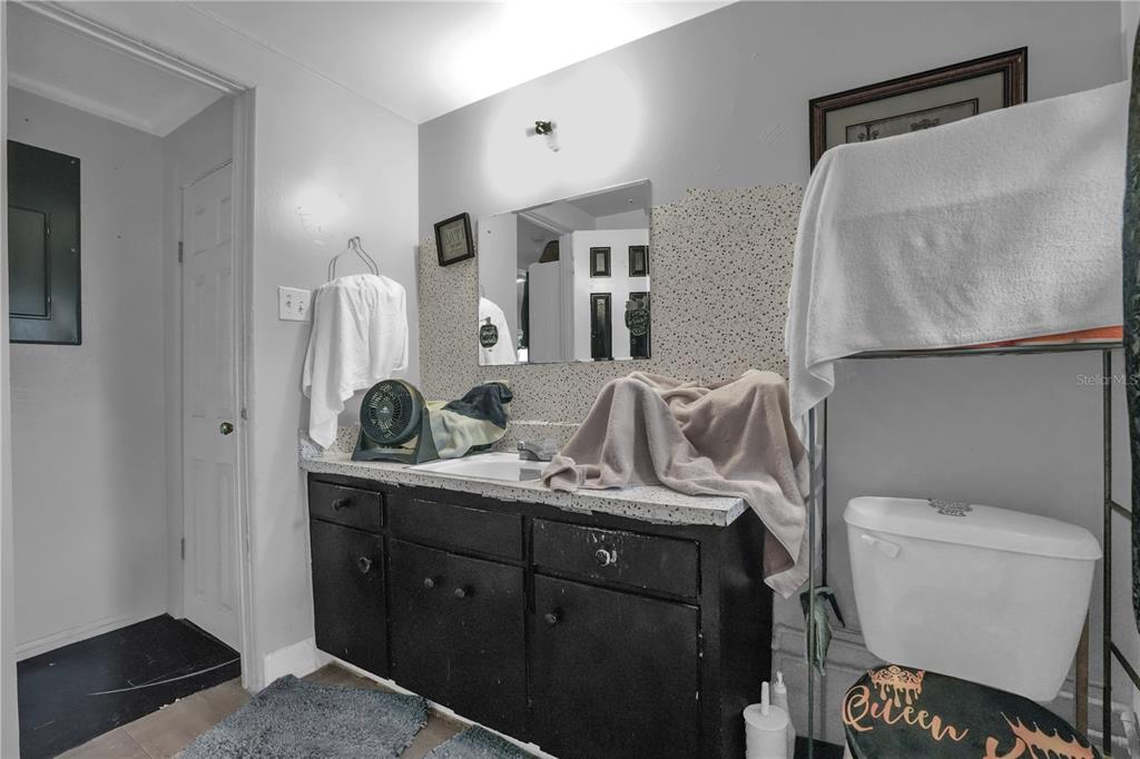 A bathroom features a black vanity, a speckled countertop, a mirror, and a toilet — 1113 S LEE AVENUE, ORLANDO, FL