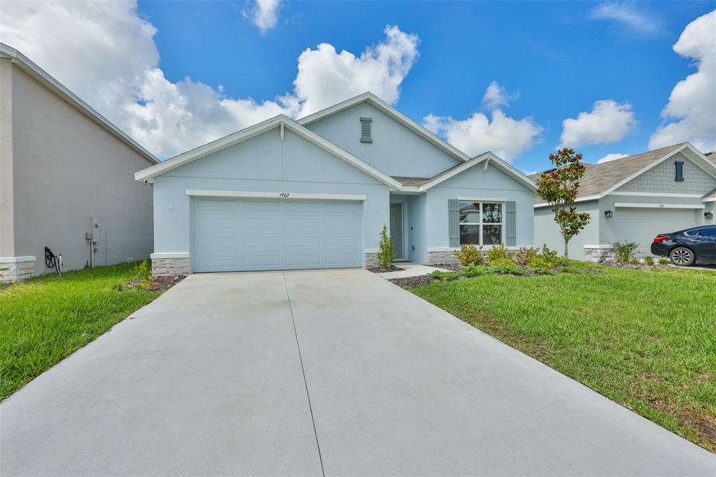 A light blue single-story house with a two-car garage and a concrete driveway — 1902 TAHITIAN SUNRISE DRIVE, PLANT CITY, FL