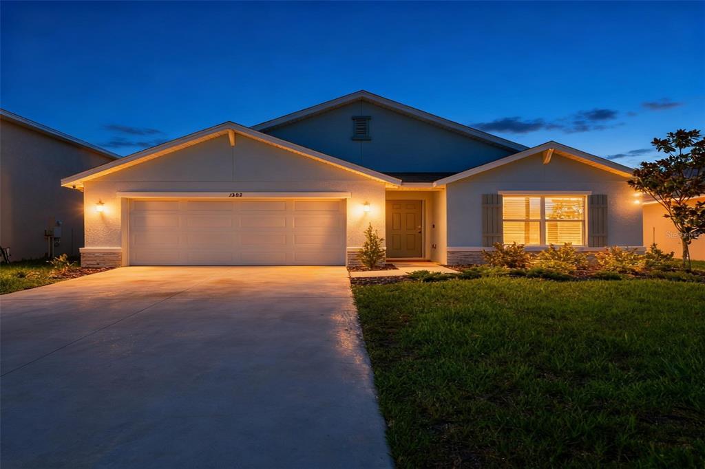 A single-story house with a two-car garage and a concrete driveway at dusk — 1902 TAHITIAN SUNRISE DRIVE, PLANT CITY, FL