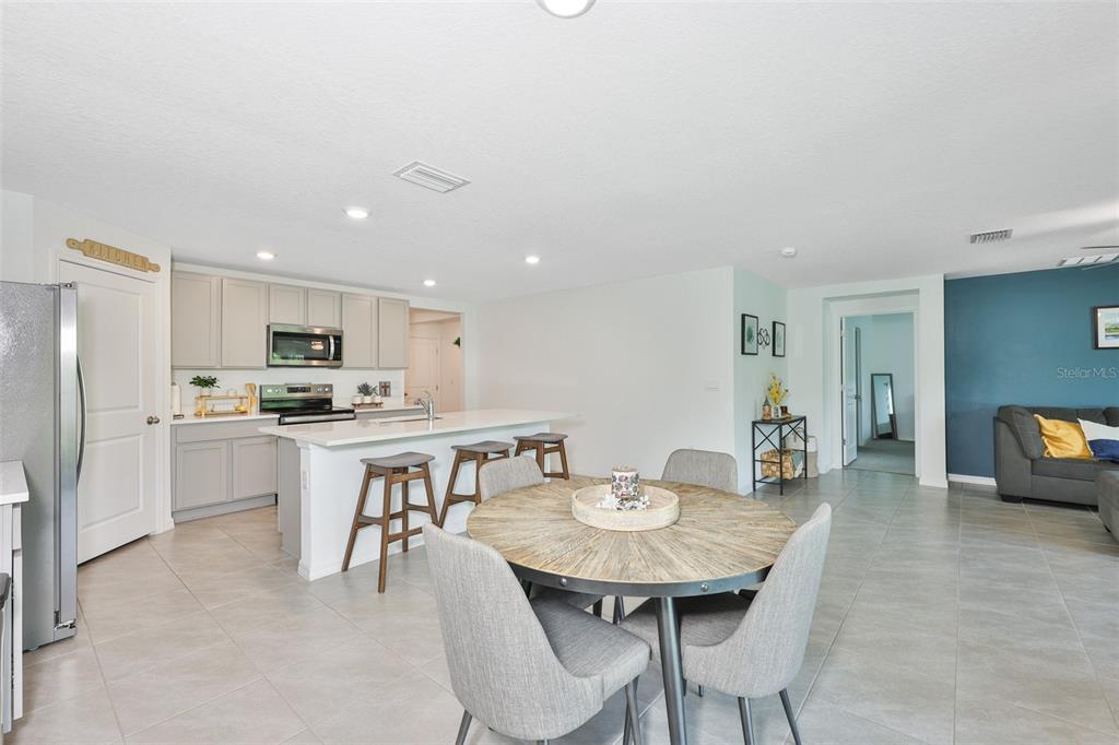 An open-concept kitchen and dining area features light gray cabinets, a kitchen island, and tile flooring — 1902 TAHITIAN SUNRISE DRIVE, PLANT CITY, FL