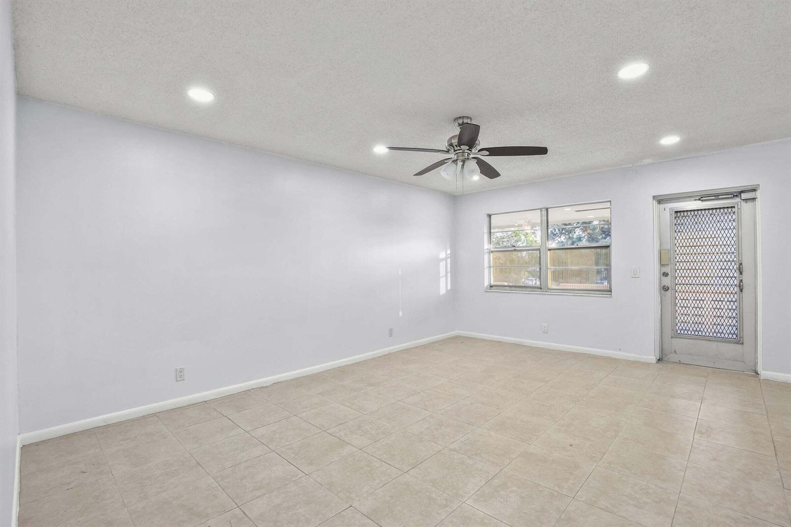An empty room with light-colored walls, tile flooring, a ceiling fan, and a glass door — 63 Hastings D, West Palm Beach FL 33417, WEST PALM BEACH, FL