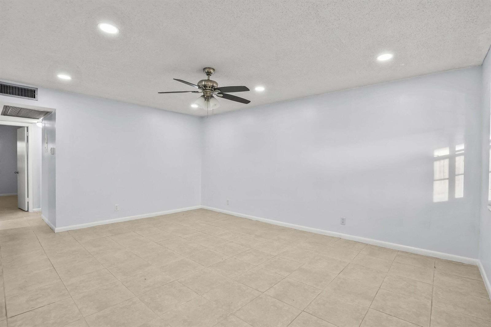 An empty room with light blue walls, tile flooring, and a ceiling fan — 63 Hastings D, West Palm Beach FL 33417, WEST PALM BEACH, FL