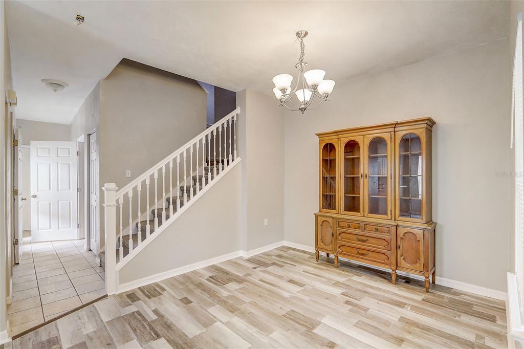 A dining area features light wood-look flooring, a wooden hutch, and a staircase with white railings — 5116 NW 21ST DRIVE, GAINESVILLE, FL