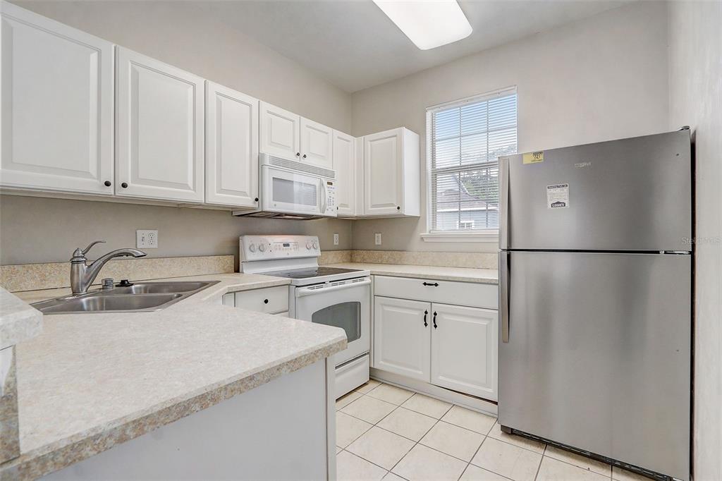 A kitchen with white cabinets, stainless steel appliances, and light-colored countertops — 5116 NW 21ST DRIVE, GAINESVILLE, FL
