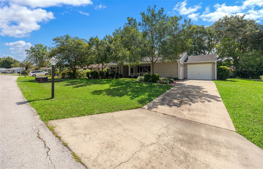 A single-story house with a beige exterior, a white garage door, and a concrete driveway — 10889 SW 90TH COURT, OCALA, FL