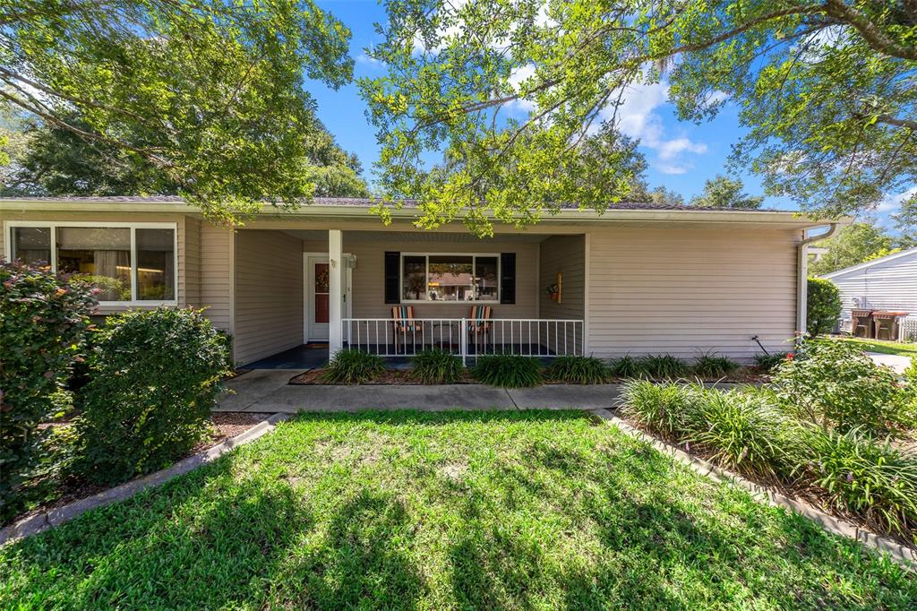 A single-story house with beige siding, a covered front porch, and a grassy front yard — 10889 SW 90TH COURT, OCALA, FL