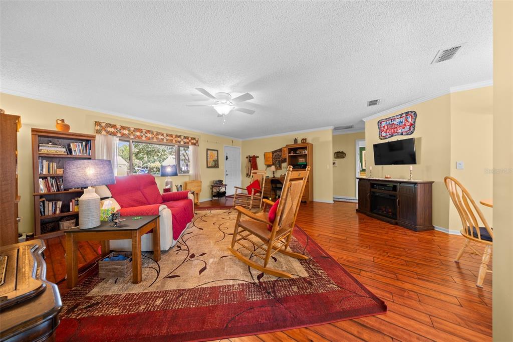 A living room features hardwood floors, a red sofa, two wooden rocking chairs, and bookshelves — 10889 SW 90TH COURT, OCALA, FL