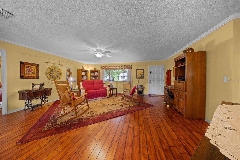 A living room features hardwood floors, a red sofa, two rocking chairs, and a hutch — 10889 SW 90TH COURT, OCALA, FL