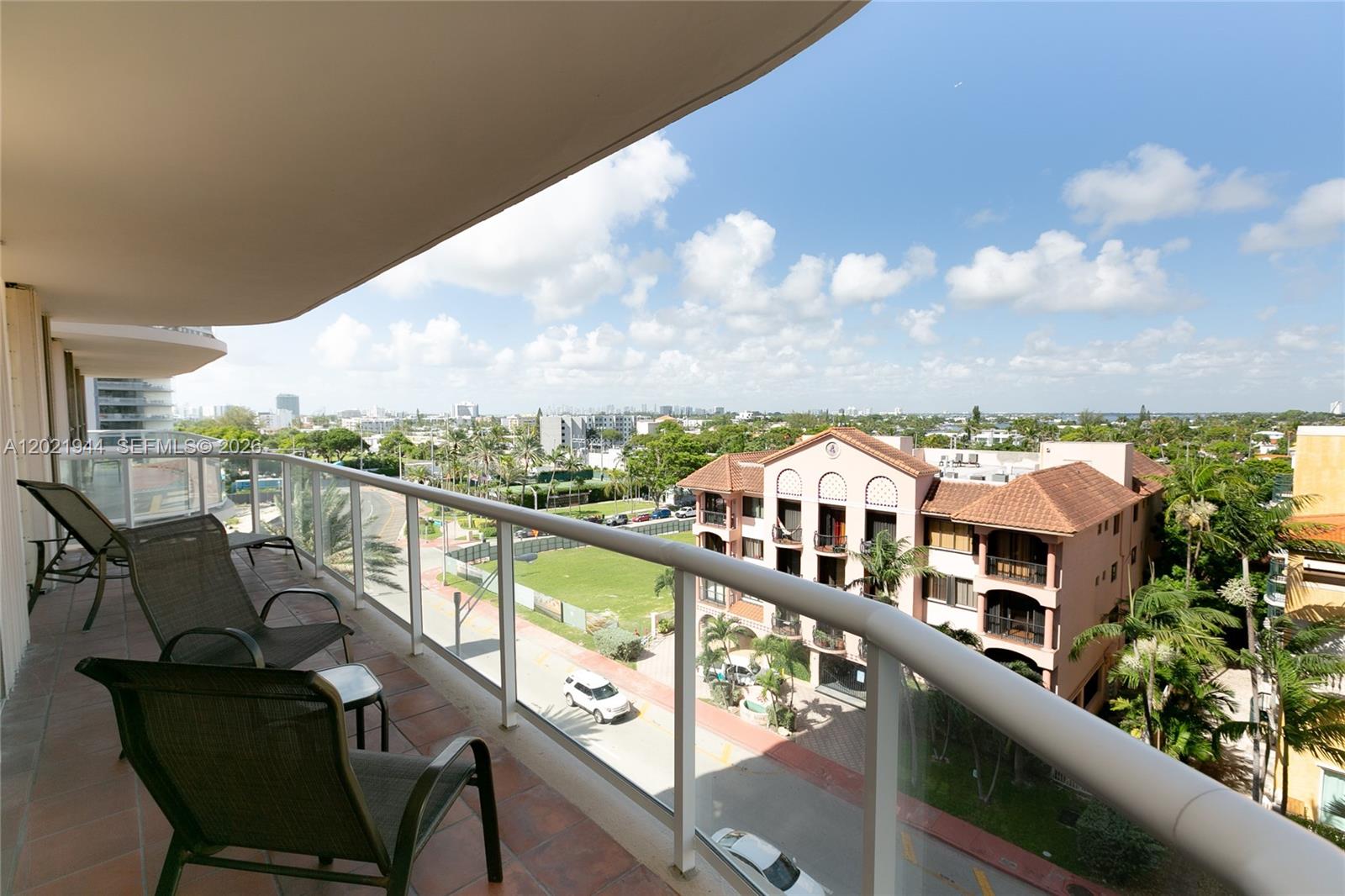 A palm tree stands on a sandy path leading to the ocean under a blue sky — 8855 Collins Ave # 6F, Surfside FL 33154, SURFSIDE, FL