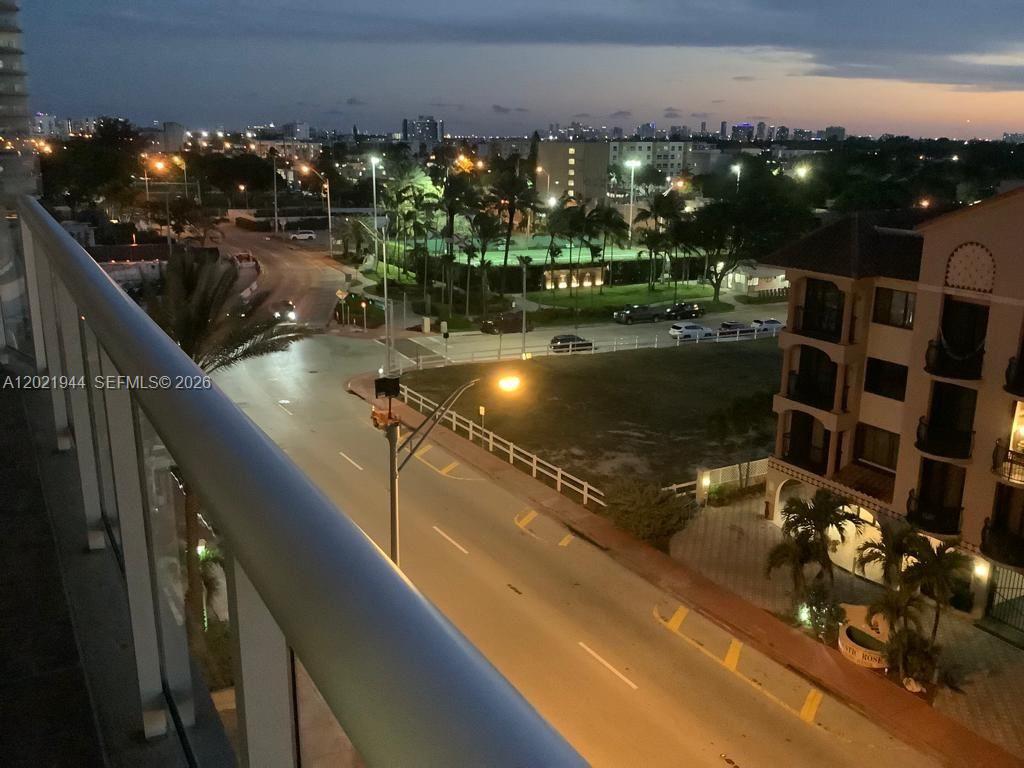A balcony with outdoor seating overlooks a street, a park, and nearby residential buildings — 8855 Collins Ave # 6F, Surfside FL 33154, SURFSIDE, FL