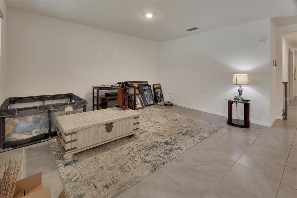 A living room features light tile flooring, a large area rug, and a central coffee table — 1235 WINTER GRAY CIRCLE, DELTONA, FL