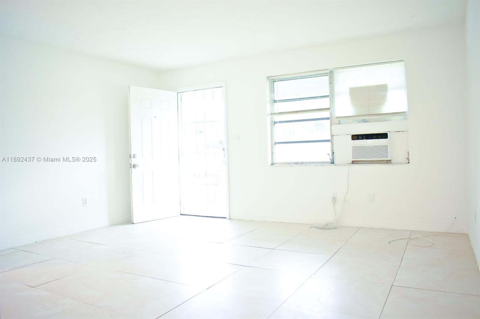 An empty room features white walls, light-colored tile flooring, an open door, and a window — 2265 NW 98th St # 2265, Miami FL 33147, MIAMI, FL