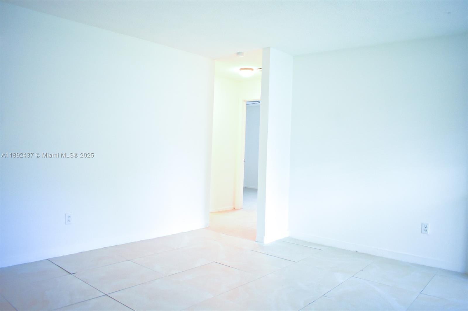 An empty room features white walls, light-colored tile flooring, and a doorway leading to another area — 2265 NW 98th St # 2265, Miami FL 33147, MIAMI, FL
