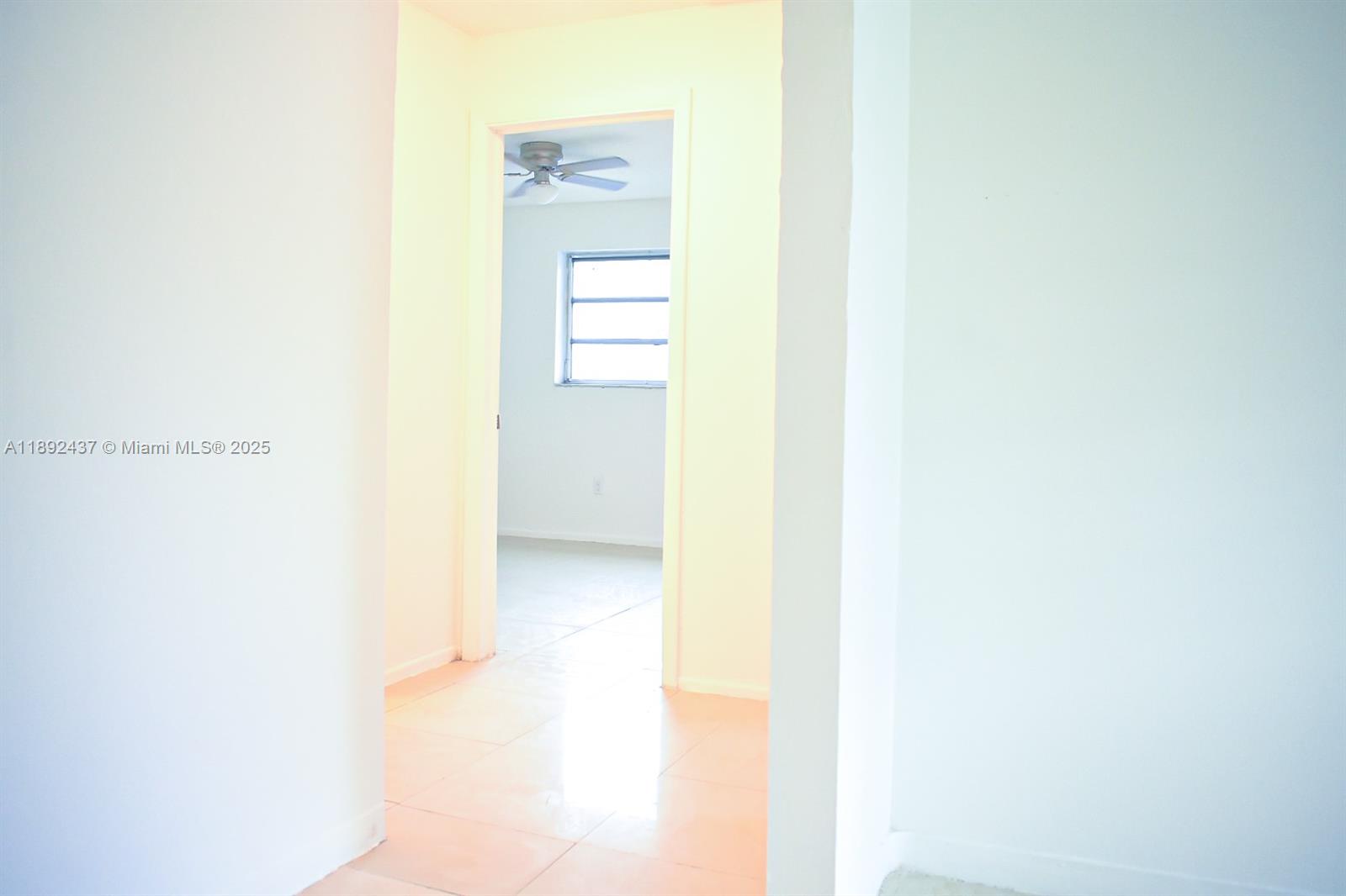 A hallway with light-colored tile flooring leads to a bedroom with a ceiling fan — 2265 NW 98th St # 2265, Miami FL 33147, MIAMI, FL
