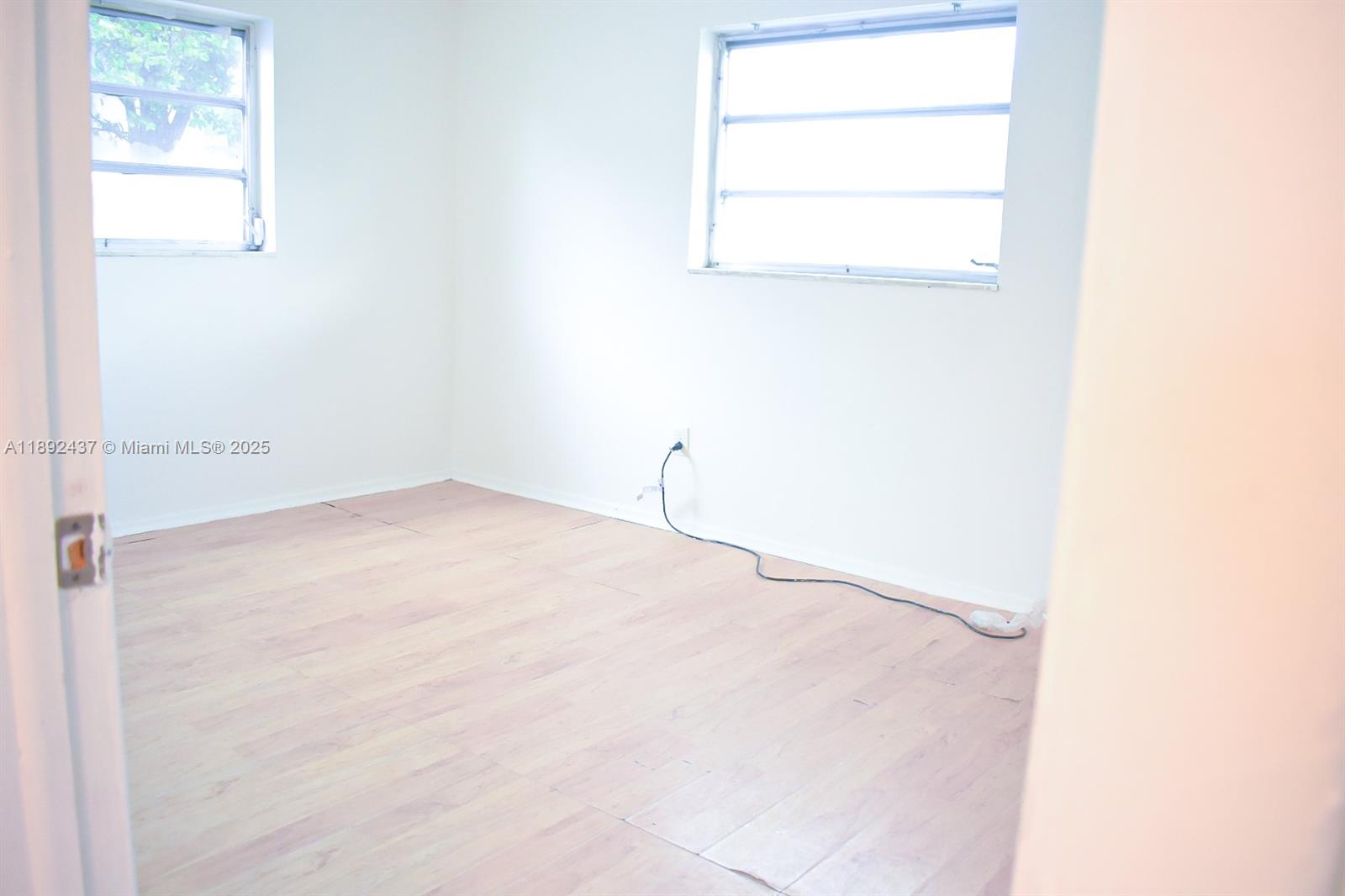 An empty room features white walls, light wood-look flooring, and two windows — 2265 NW 98th St # 2265, Miami FL 33147, MIAMI, FL