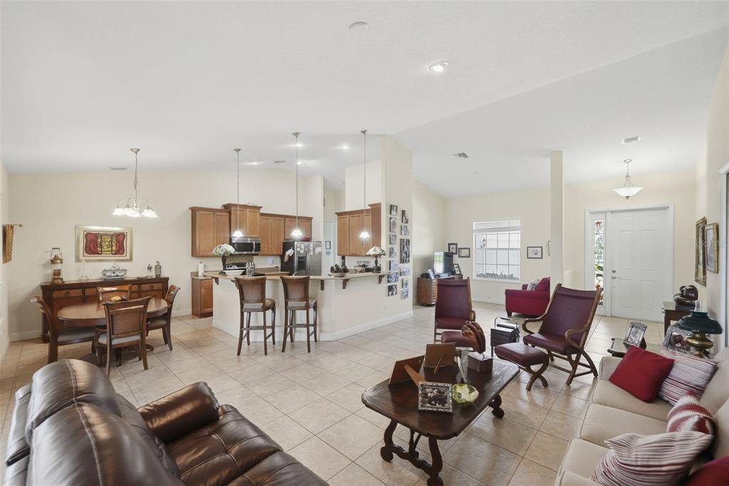 An open-concept living area features a kitchen with wood cabinets, a dining space, and tile flooring — 598 GOSSAMER WING WAY, SEBASTIAN, FL