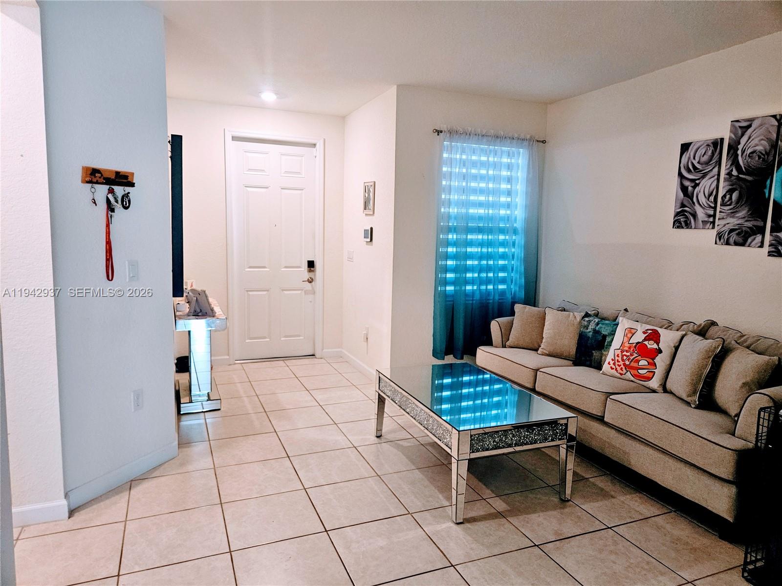 A living room features light tile floors, a beige sofa, and a mirrored coffee table — 10918 W 33rd Way, Hialeah FL 33018, HIALEAH, FL