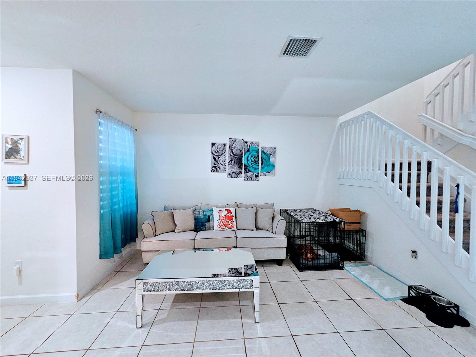 A living room features a beige sofa, a mirrored coffee table, and a dog crate — 10918 W 33rd Way, Hialeah FL 33018, HIALEAH, FL