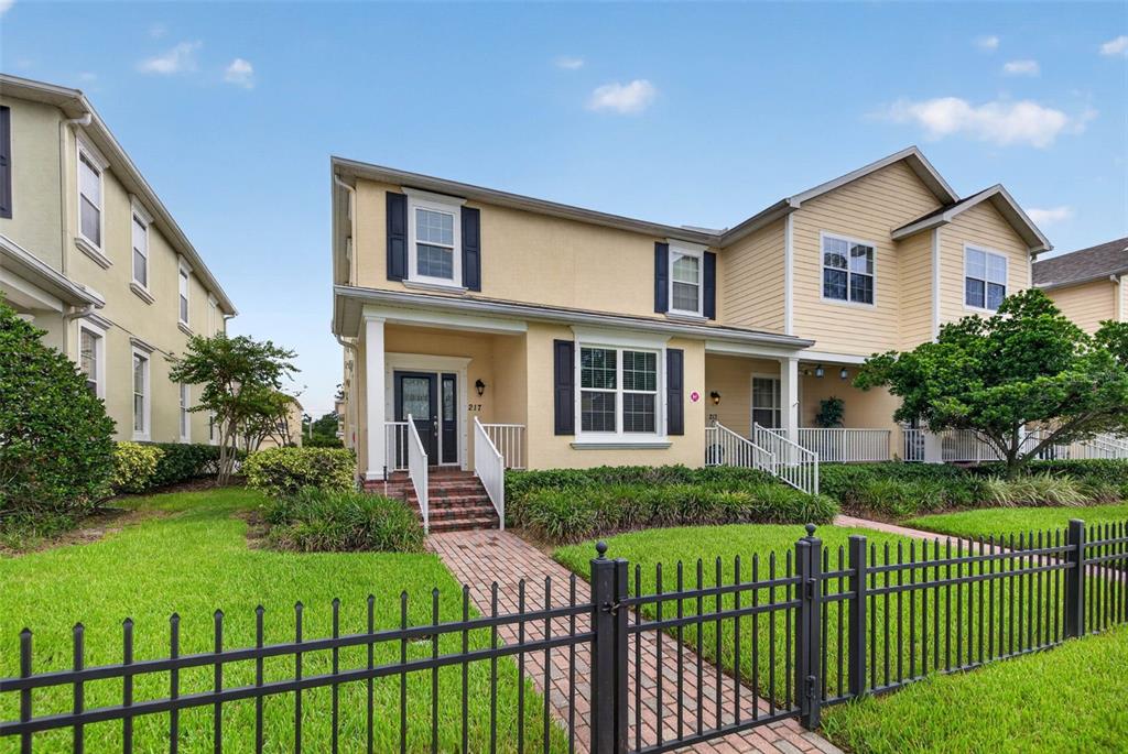 A two-story yellow house with a brick walkway and black metal fence in the front — 217 49TH AVENUE N, ST PETERSBURG, FL
