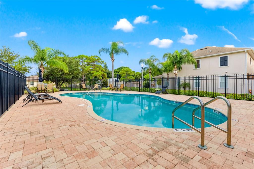 An outdoor swimming pool with a paved deck, lounge chairs, and a black metal fence — 217 49TH AVENUE N, ST PETERSBURG, FL