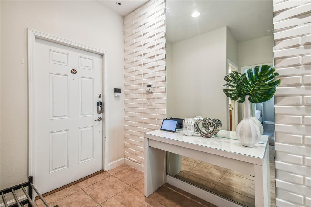 An entryway features a white door, a glass-topped console table, and a textured accent wall — 8841 CANDY PALM ROAD, KISSIMMEE, FL