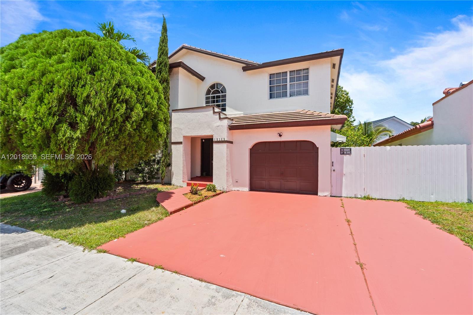 A two-story house features a red driveway, a brown garage door, and a white fence — 15345 SW 63rd Ter, Miami FL 33193, MIAMI, FL