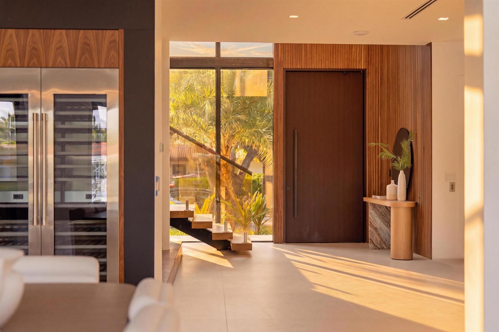 An entryway features a wood-paneled wall, a modern door, a floating console table, and stairs — 2360 NE 49th Street, Lighthouse Point FL 33064, LIGHTHOUSE POINT, FL