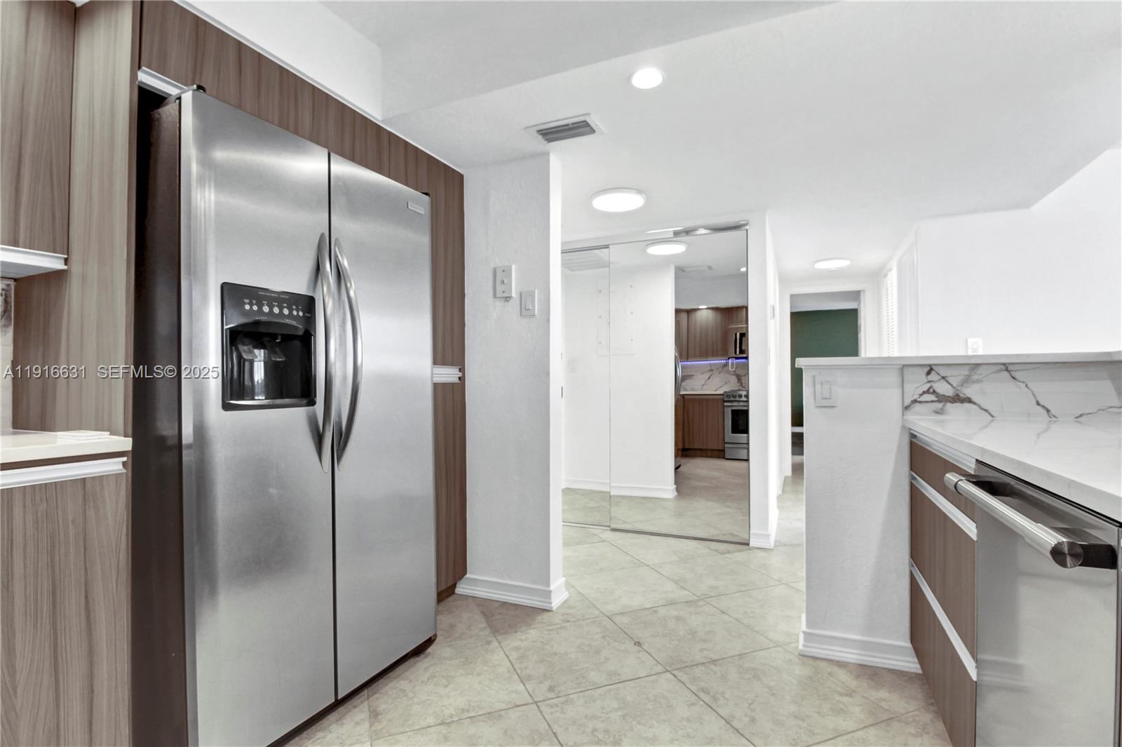 A kitchen features stainless steel appliances, wood-toned cabinetry, and white marble-style countertops — 800 Parkview Dr # 821, Hallandale Beach FL 33009, HALLANDALE BEACH, FL