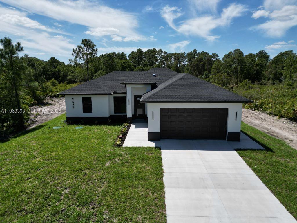 A modern single-story house with a dark roof, white stucco walls, and a two-car garage — 3505 57TH ST, Lehigh Acres FL 33971, LEHIGH ACRES, FL