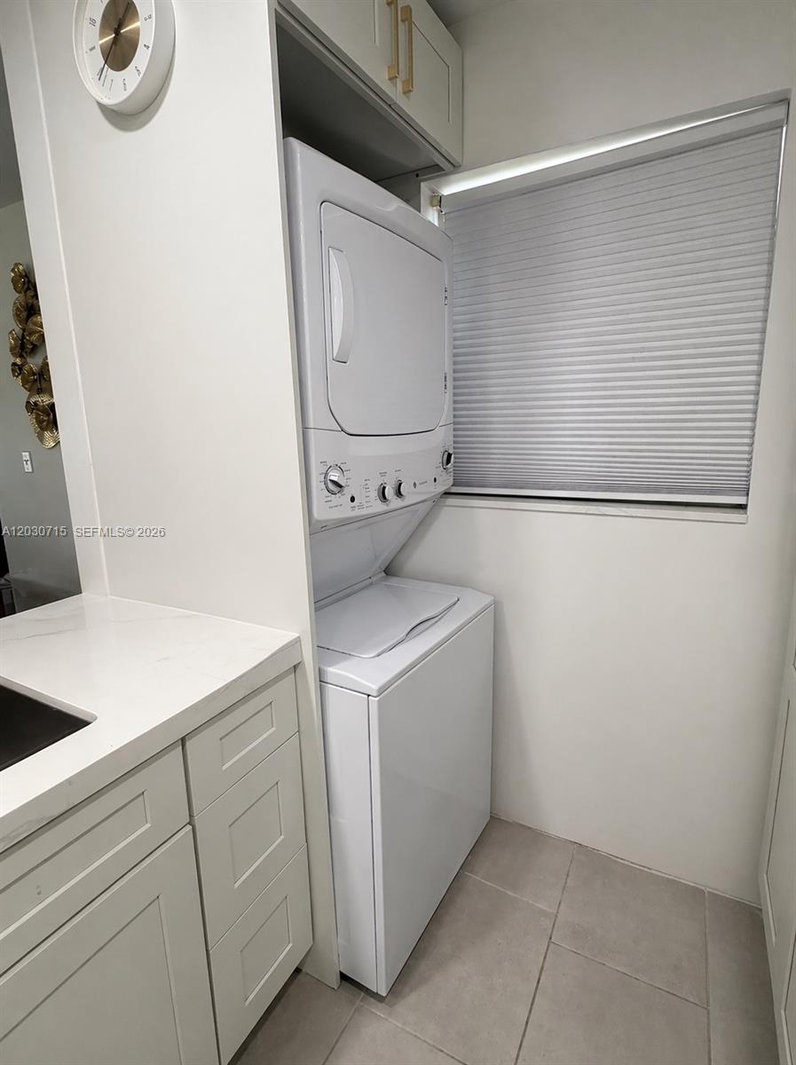 A laundry area features a stacked washer and dryer unit next to white cabinetry — 200 E High Point Ct E # D, Delray Beach FL 33445, DELRAY BEACH, FL