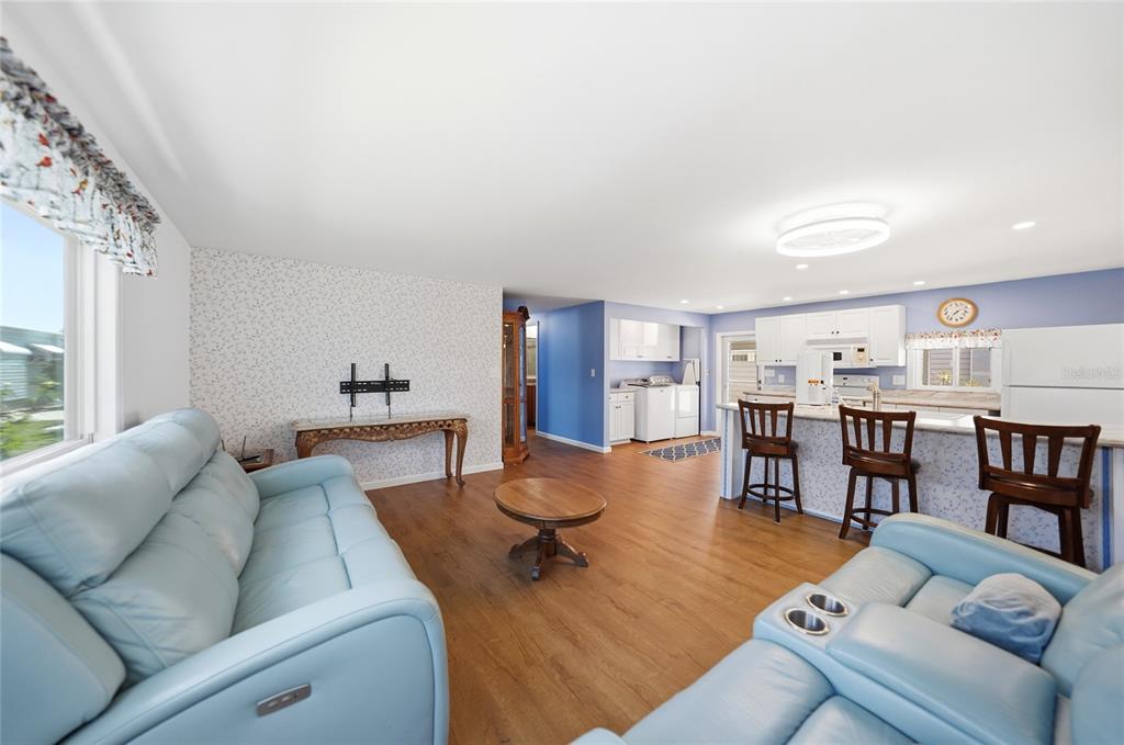 A living room with light blue sofas opens into a kitchen with a breakfast bar — 10303 BURNT STORE ROAD UNIT 108, PUNTA GORDA, FL