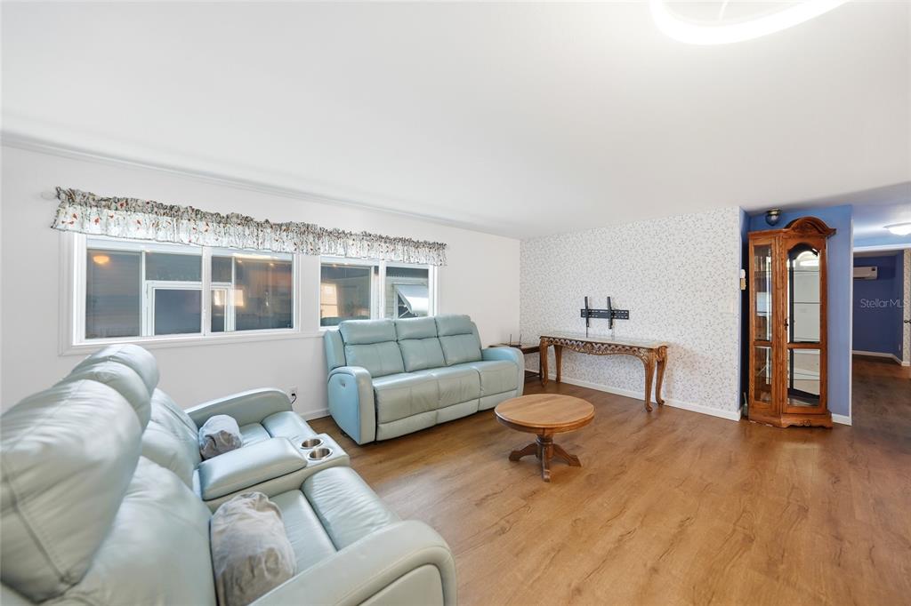 A living room features light blue leather sofas, wood-look flooring, and a patterned accent wall — 10303 BURNT STORE ROAD UNIT 108, PUNTA GORDA, FL