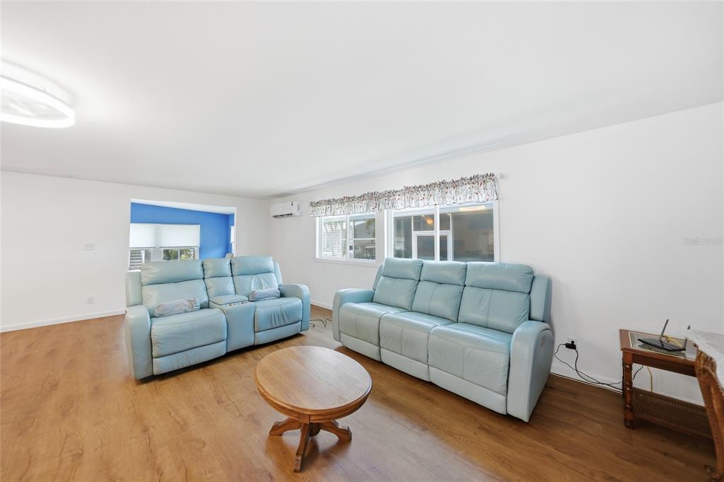 A living room features light blue leather sofas, a round wooden table, and wood flooring — 10303 BURNT STORE ROAD UNIT 108, PUNTA GORDA, FL