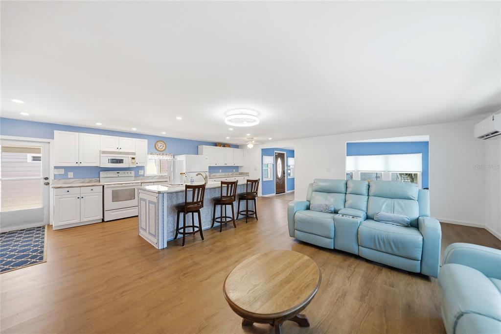 An open-concept kitchen and living area features white cabinets, a kitchen island, and blue walls — 10303 BURNT STORE ROAD UNIT 108, PUNTA GORDA, FL