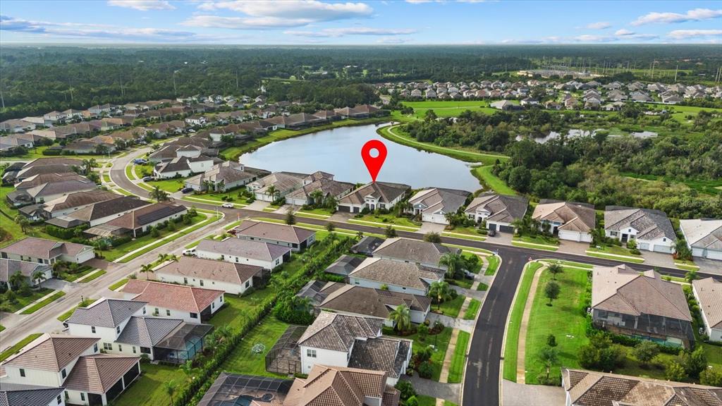 An aerial view shows a suburban neighborhood with houses surrounding a central lake — 2641 BUTTERFLY JASMINE TRAIL, SARASOTA, FL