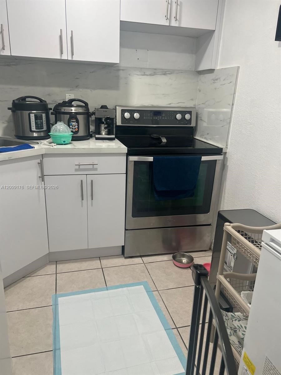 A kitchen features white cabinets, stainless steel appliances, and a marble-patterned backsplash — 801 NW 47th Ave # 503W, Miami FL 33126, MIAMI, FL