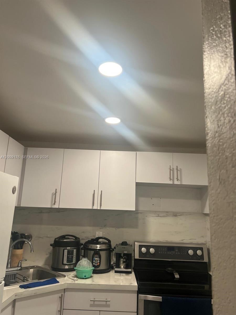 A kitchen features white cabinets, marble-look countertops, a stainless steel stove, and recessed lighting — 801 NW 47th Ave # 503W, Miami FL 33126, MIAMI, FL