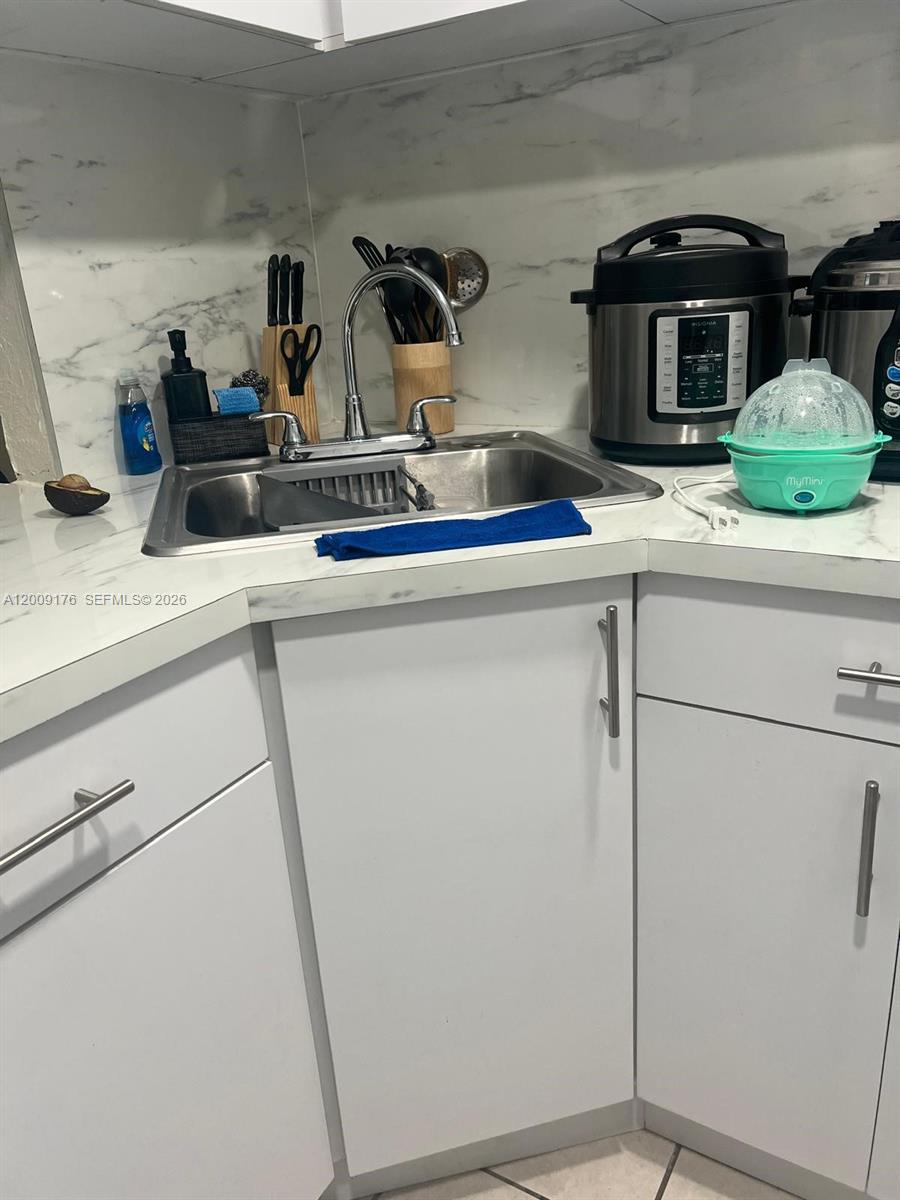 A kitchen sink with white cabinets and marble-patterned countertops — 801 NW 47th Ave # 503W, Miami FL 33126, MIAMI, FL