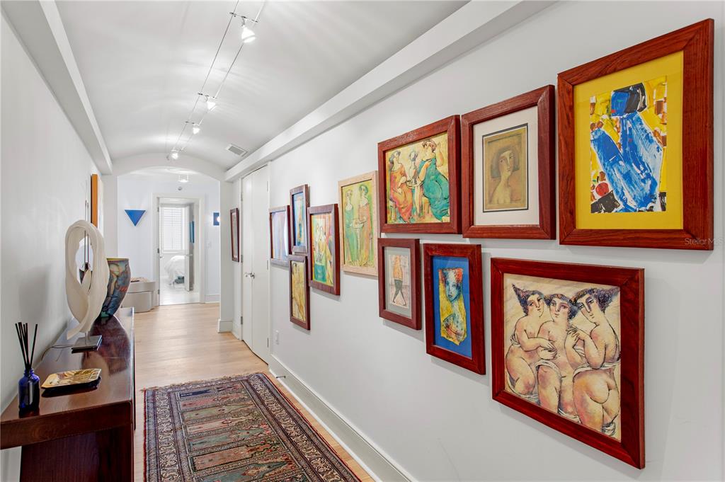 A hallway with a vaulted ceiling, hardwood floors, a runner rug, and a gallery wall — 775 LONGBOAT CLUB ROAD UNIT 808, LONGBOAT KEY, FL