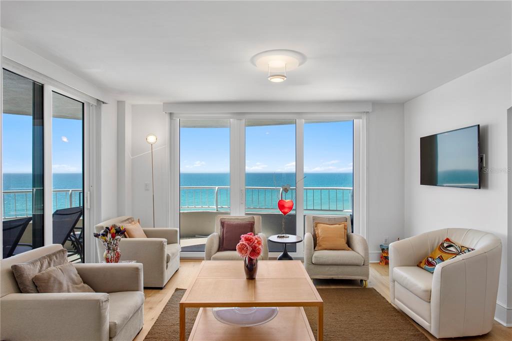 A living room features four armchairs, a wooden coffee table, and floor-to-ceiling windows overlooking the ocean — 775 LONGBOAT CLUB ROAD UNIT 808, LONGBOAT KEY, FL