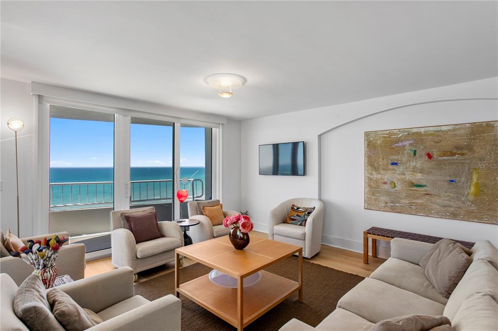 A living room features light-colored furniture, a wooden coffee table, and a view of the ocean — 775 LONGBOAT CLUB ROAD UNIT 808, LONGBOAT KEY, FL