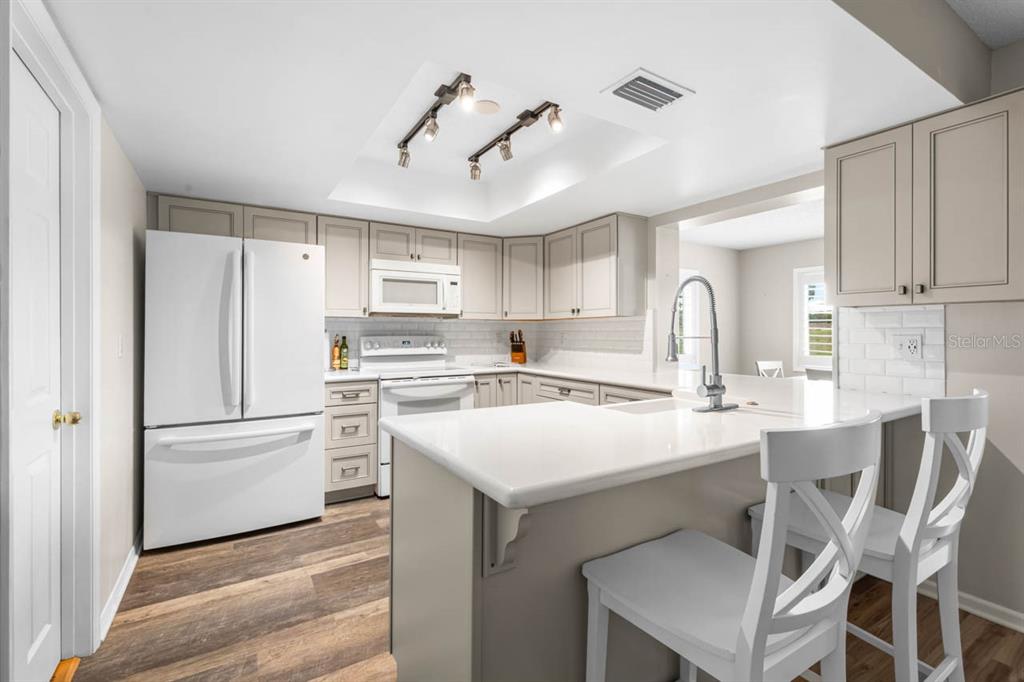 A kitchen with white appliances, light gray cabinets, white countertops, and a breakfast bar — 1226 HADDINGTON CIRCLE, SUN CITY CENTER, FL